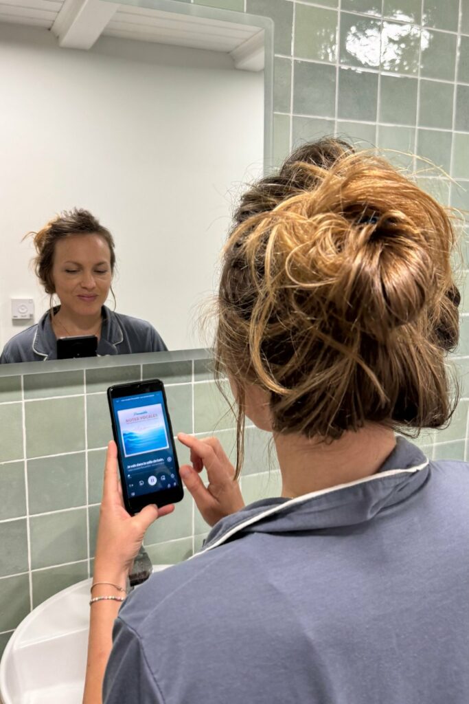 Camille Montaz écoute une note vocale Peaussible sur son téléphone, devant le miroir de sa salle de bain